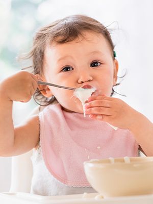 Baby isst Joghurt und kleckert