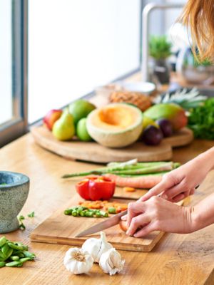 Frau in weißem T Shirt schneidet Gemüse in der Küche