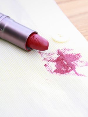 Roter Lippenstift liegt auf Tuch mit Lippenstiftfleck