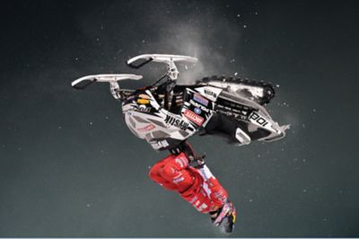 person flipping upside down on snowmobile