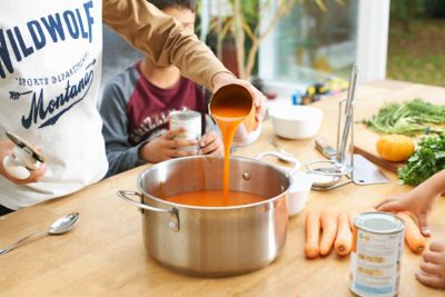 un individu verse la sauce d'une boîte de conserve dans une casserole