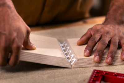 Una persona aplica pegamento a piezas de madera.