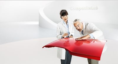 Two scientists examine the red roof panel of a roadster