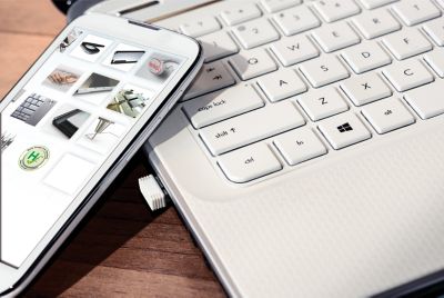 Photo of white smartphone resting on the edge of a white laptop keyboard the screen of the smartphone is photoshopped  to disply henkel adhesive products, applications and standards