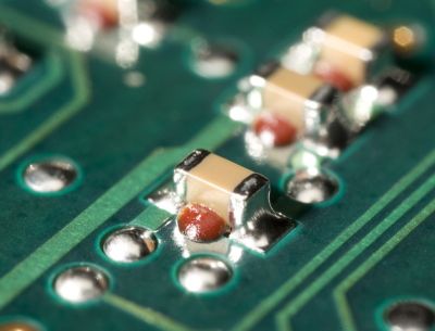 Photo of small surface mount  electrical components on a green printed circuit board using henkel surface mount adhesive solutions