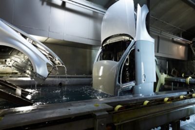 Car body being lifted out of a surface treatment bath in automotive manufacturing line