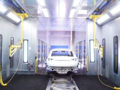 White car body undergoing Henkel's Two-Step Surface Treatment process during the manufacturing process.