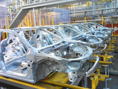 Row of white car frames inside automotive manufacturing site