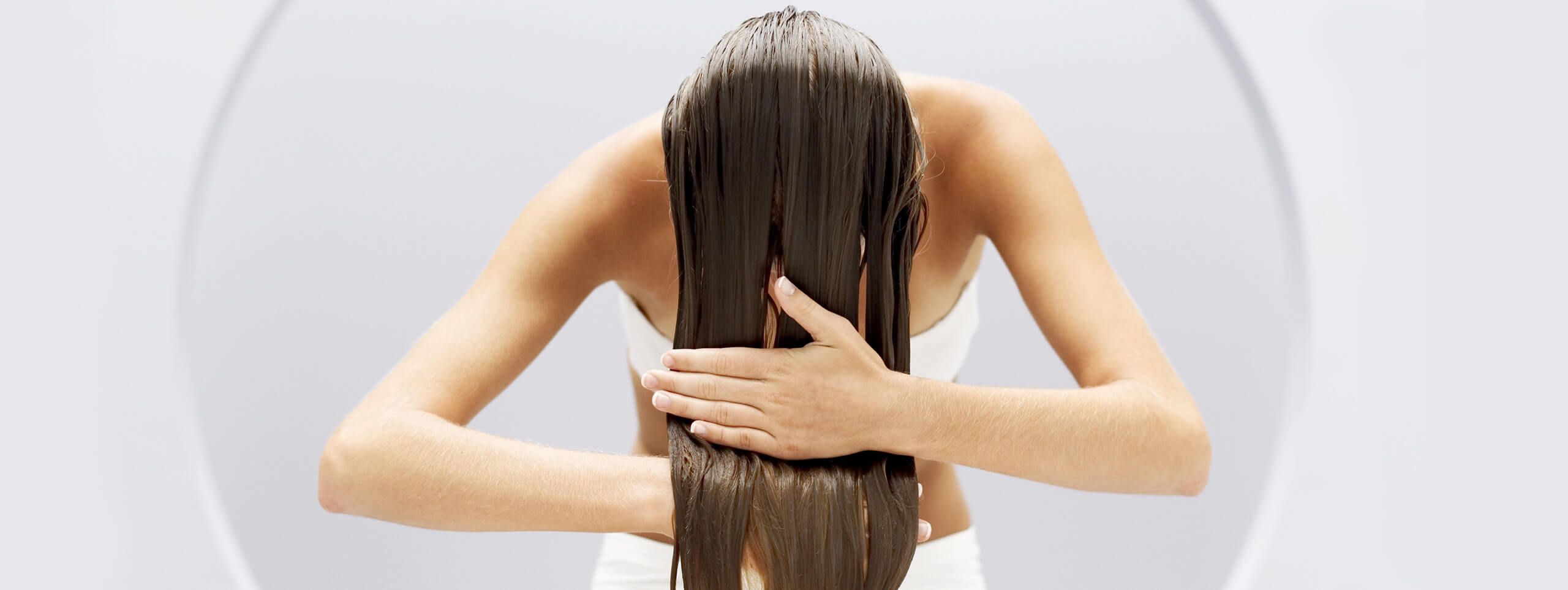 Woman applies hair treatment to long hair