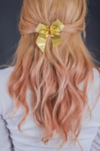 A young woman with pink wavy hair with a yellow bow, pictured from behind