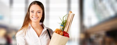 Woman reading the contents of a pizza box in the freezer section of the grocery store